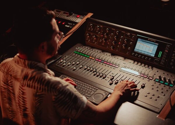 Man sitting inside a sound recording studio controlling recording