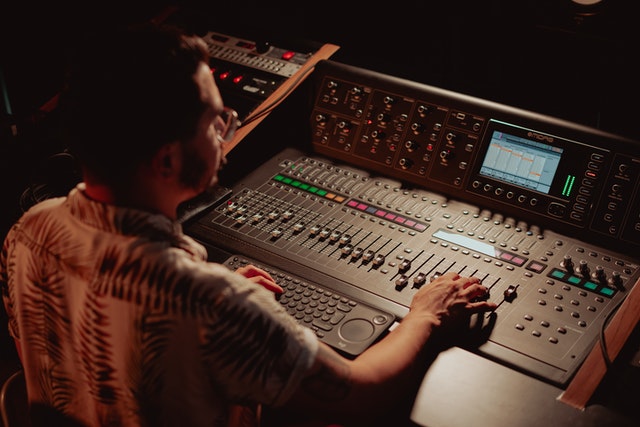 Man sitting inside a sound recording studio controlling recording